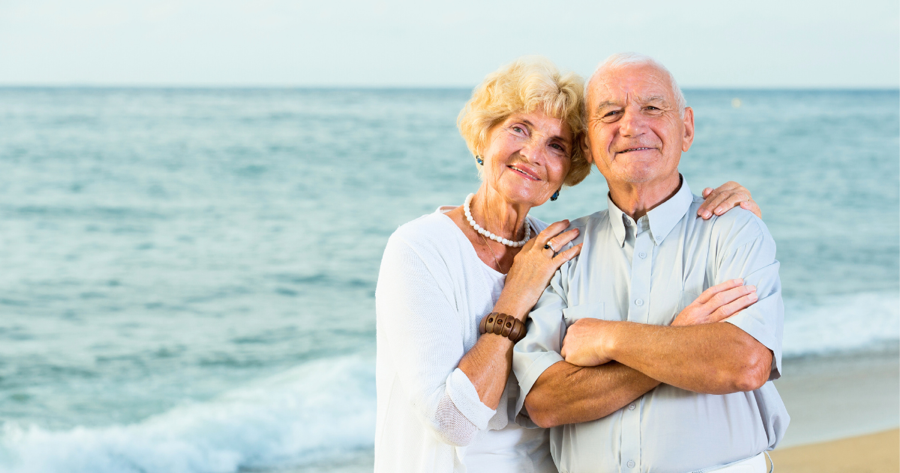 Elderly couple standing on a beach. 